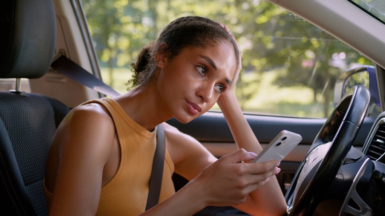 Driver staring ahead with phone in hand looking frustrated