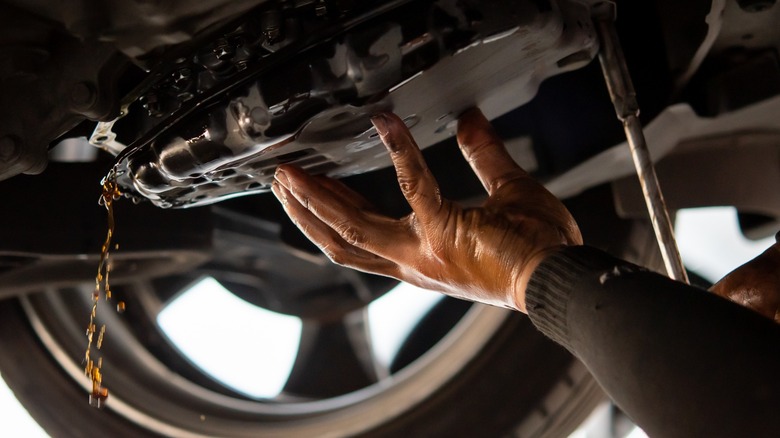 Close up of mechanic draining fluid from transmission