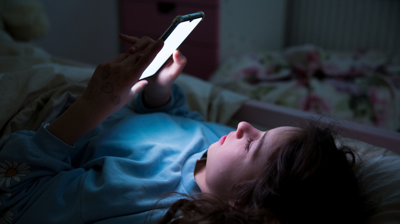 A child using smart phone lying in bed late at night