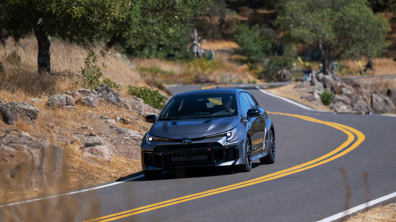 A gray 2026 Toyota GR Corolla driving on a rural road.