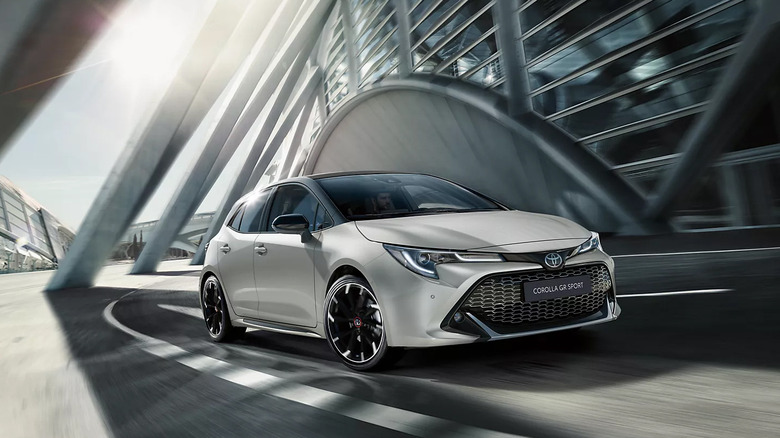 A white Toyota Corolla GR Sport driving in a city.