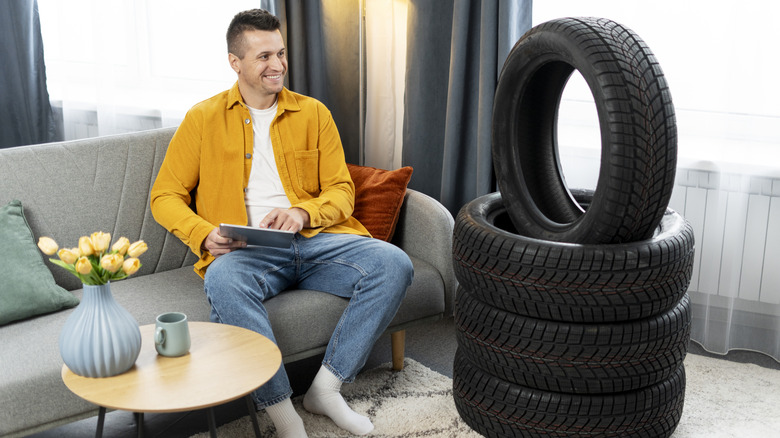 Man sitting on sofa with tablet looking at tires in his living room