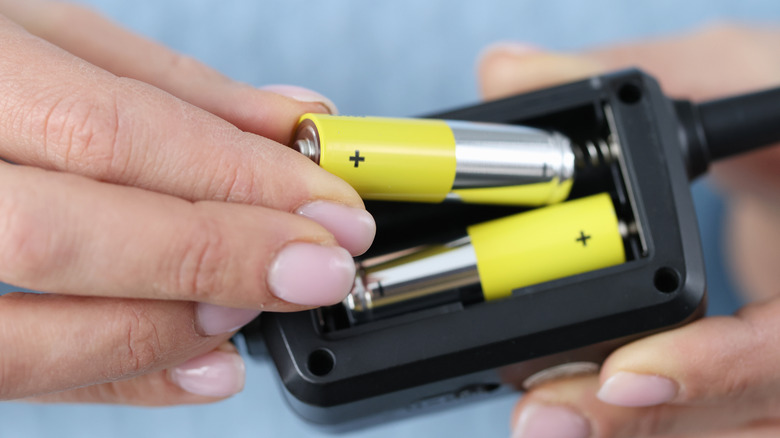 Hands placing batteries in device