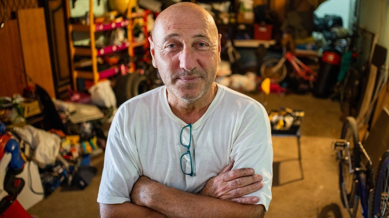 Man poses in front of cluttered garage