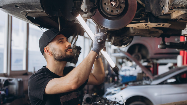Auto mechanic working on vehicle.