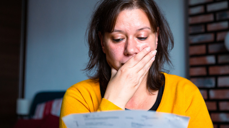 Woman looking at bill with surprised expression.