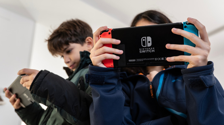 Boy and a girl playing on Switch consoles