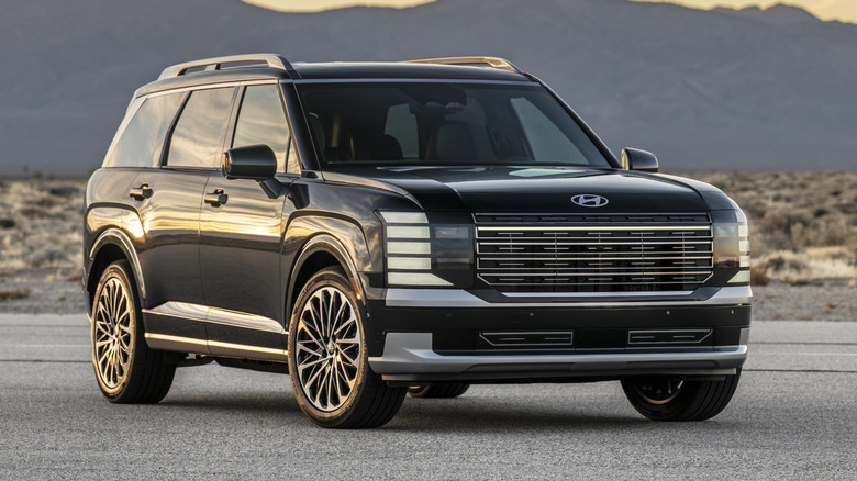 Black 2026 Hyundai Palisade Hybrid parked on a desert road at sunset