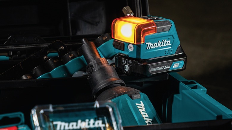 A Makita 12V work light glowing yellow atop an open tool box.
