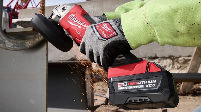 A person using a Milwaukee grinder on metal.