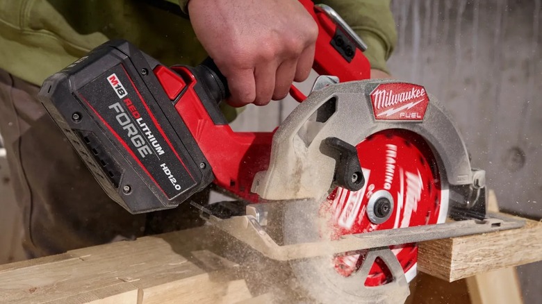 A person cutting wood with a Milwaukee circular saw.