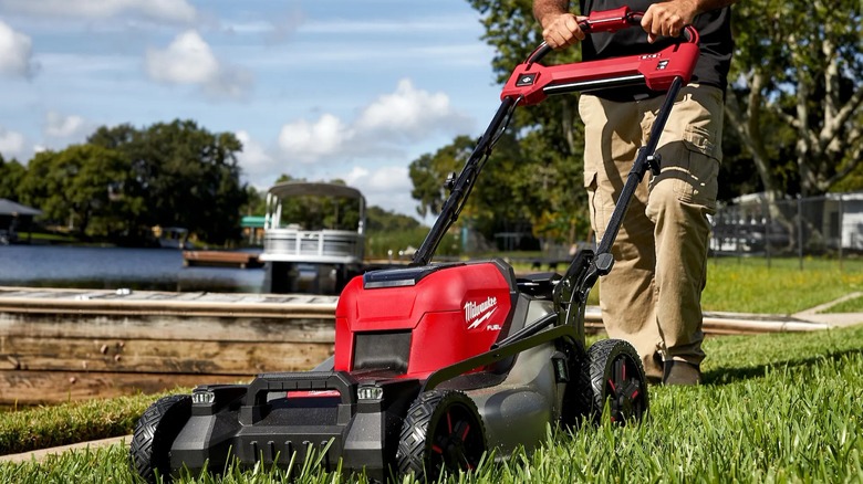 A person pushing a Milwaukee lawn mower.