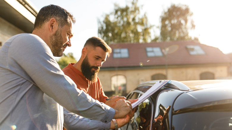 Two people discussing next to car