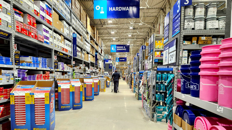 The interior of a Lowe's store with one person in the background pushing a shopping cart