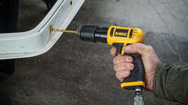 A person using a DeWalt pneumatic reversible drill.