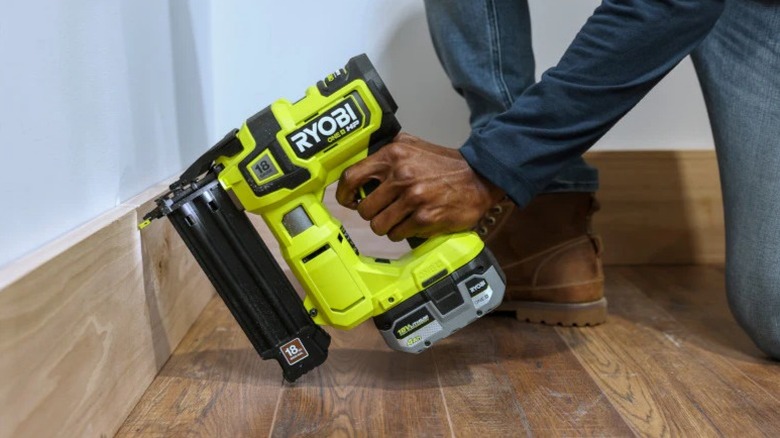 Person using Ryobi One+ 18V HP Brushless Brad Nailer on baseboard