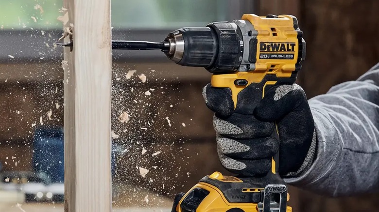 A person using a DeWalt drill/driver on wood.