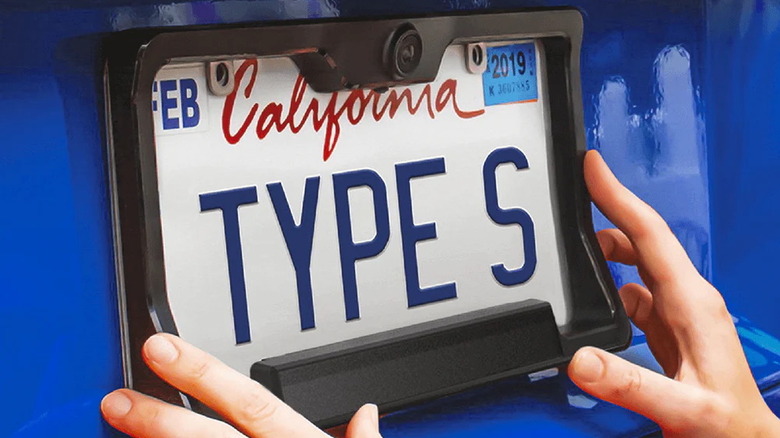 person installing a Type S HD Solar-Powered Backup Camera on their rear license plate