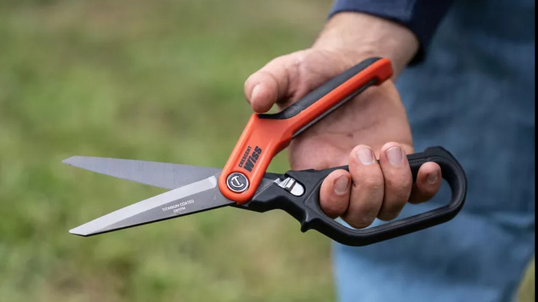 A close-up of a man holding a set of Crescent heavy-duty tradesman shears