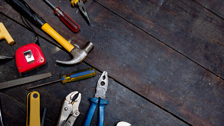 A random collection of hand tools on a dark wood surface