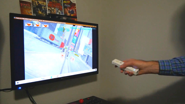 A person, mostly off-screen, using a Wii Remote to play a PC game on a TV.