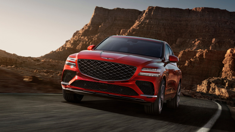 A red Genesis GV80 Coupe being driven down a rural desert road.