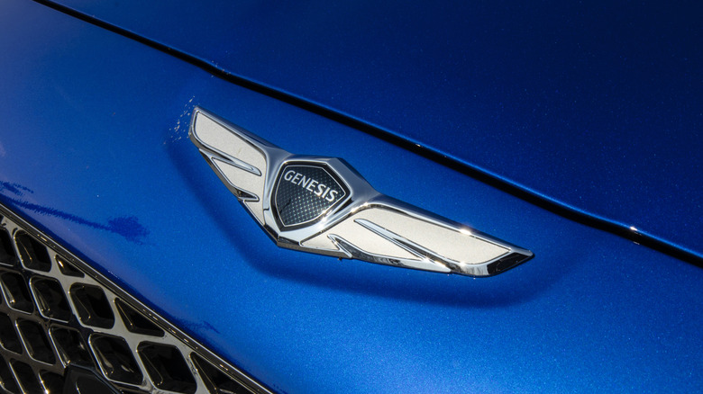 A close-up of a metallic blue front-end Genesis vehicle with a chrome Genesis badge.
