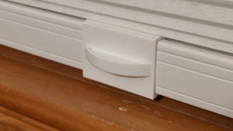 A 3D-printed handle attached to a closed cellular shade, set against a wooden windowsill