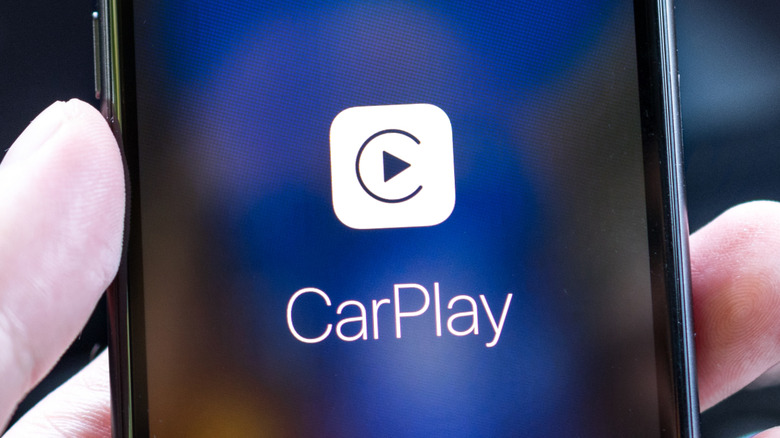 A person holding an iPhone running CarPlay.