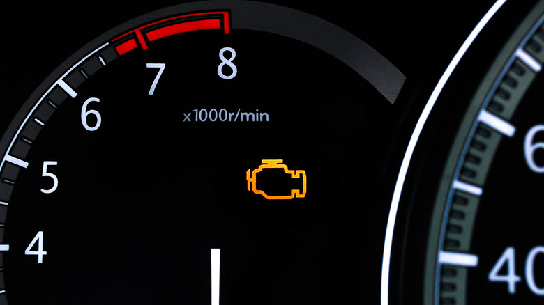 Closeup of a car dashboard with an illuminated check engine light