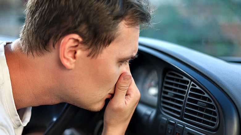 A driver holding his nose from a car bad smell