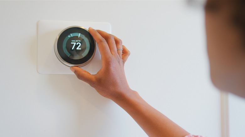 Person adjusting smart thermostat