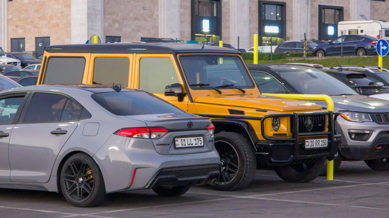 A big yellow SUV, a gray sedan, and a small SUV all parked next to each other.