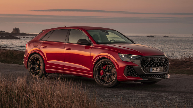 A brand-new 2027 Audi RS Q8 parked seaside during a sunset, front 3/4 view