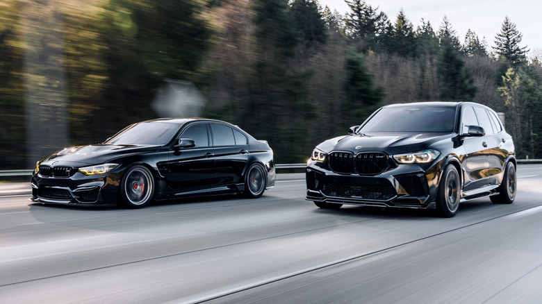 A black BMW X5 SUV driven next to a black BMW M3.