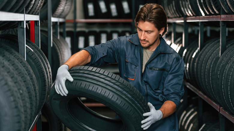 Tire technician in tire store holding a tire