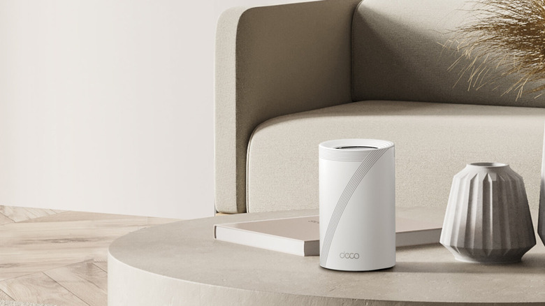 A TP-Link Deco 7 Pro on a low height table in front of a sofa.