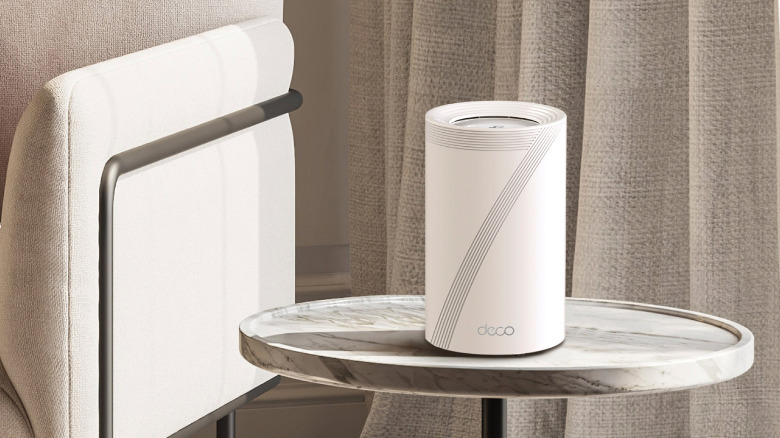 A TP-Link Deco 7 Pro wi-fi mesh router on a table in a living room.