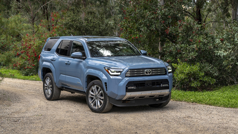 A blue 2026 Toyota 4Runner on a gravel road in a wooded area