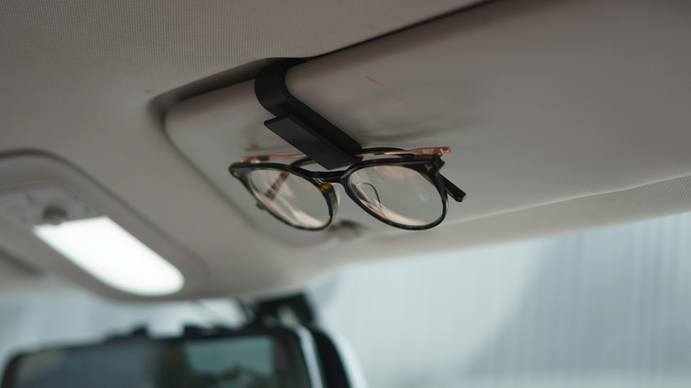 A 3D-printed sunglass holder attached to the sun visor inside a car.