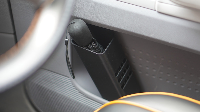 A 3D-printed umbrella holder inside a car's front door pocket.