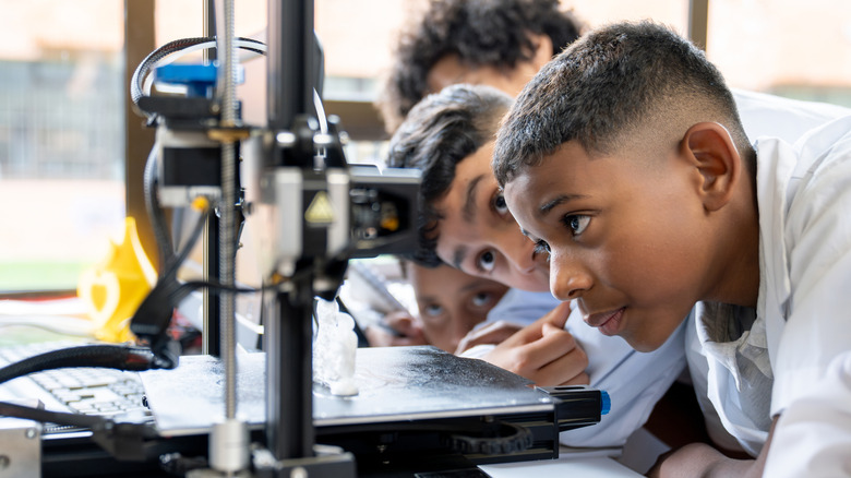 Students examining an FDM 3D printer