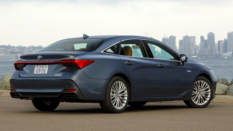 Rear 3/4 view of blue Toyota Avalon Hybrid parked in front of harbor.
