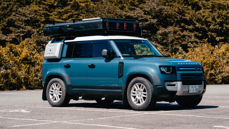 A blue modified Land Rover Defender parked in a car park.