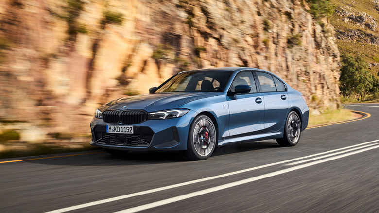 2026 BMW 3 Series sedan in blue on a mountain road, front 3/4 view