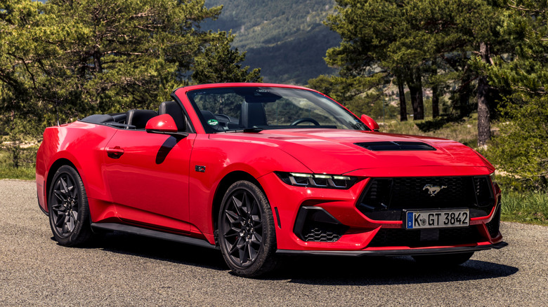 Front 3/4 view of Ford Mustang GT convertible in forested mountainous setting