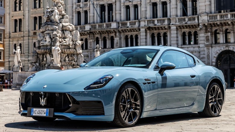 Front 3/4 view of Maserati GranTurismo stopped on road with rock background