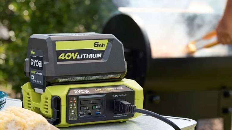 Person grilling while Ryobi power bank charges a 40V battery