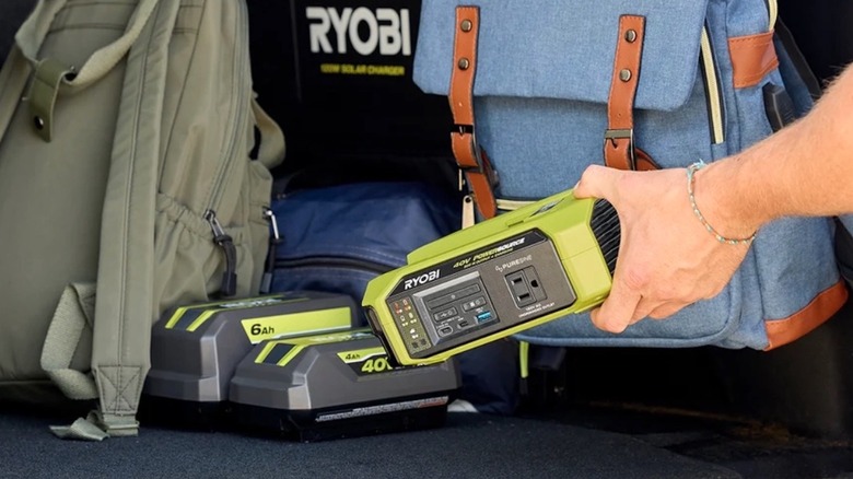Person placing a Ryobi 300W charger and power bank next to 40V batteries