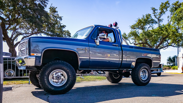 Front 3/4 view of Chevy square body 4x4 truck at car show.